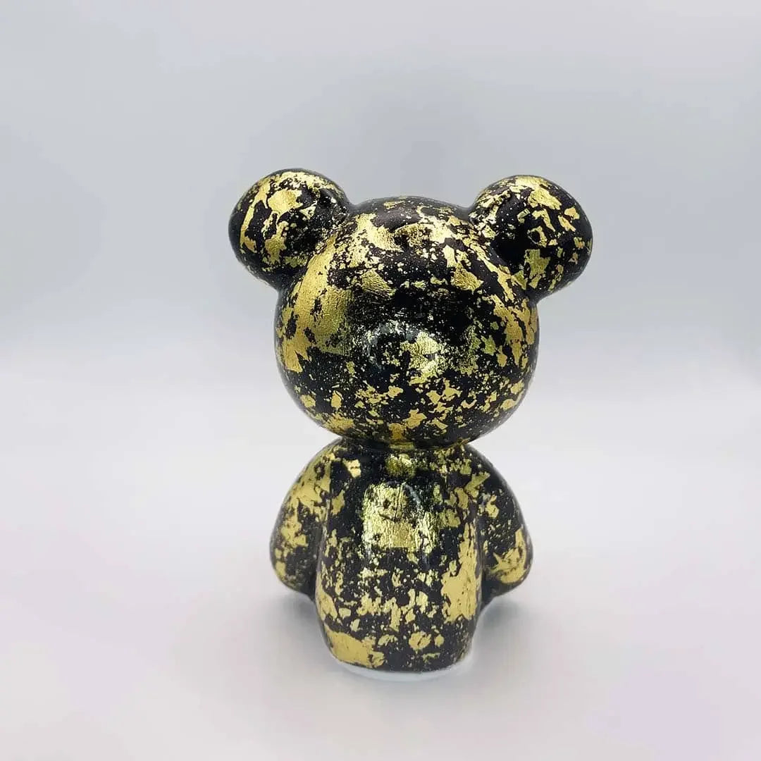 Black and gold decorative object resembling a bear on a white background