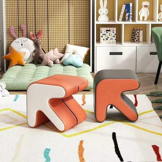 Arrow Leather Ottoman in a room with a bookshelf and decorative items.