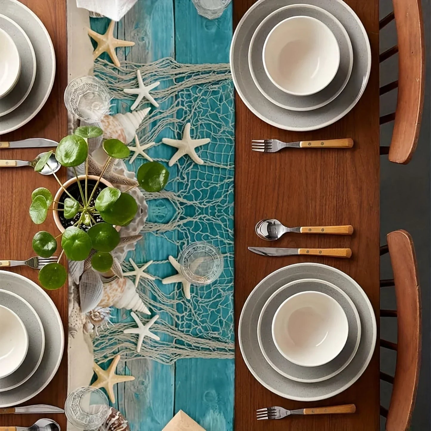 Dining table setting with coastal decor, including starfish, seashells, and a blue runner.