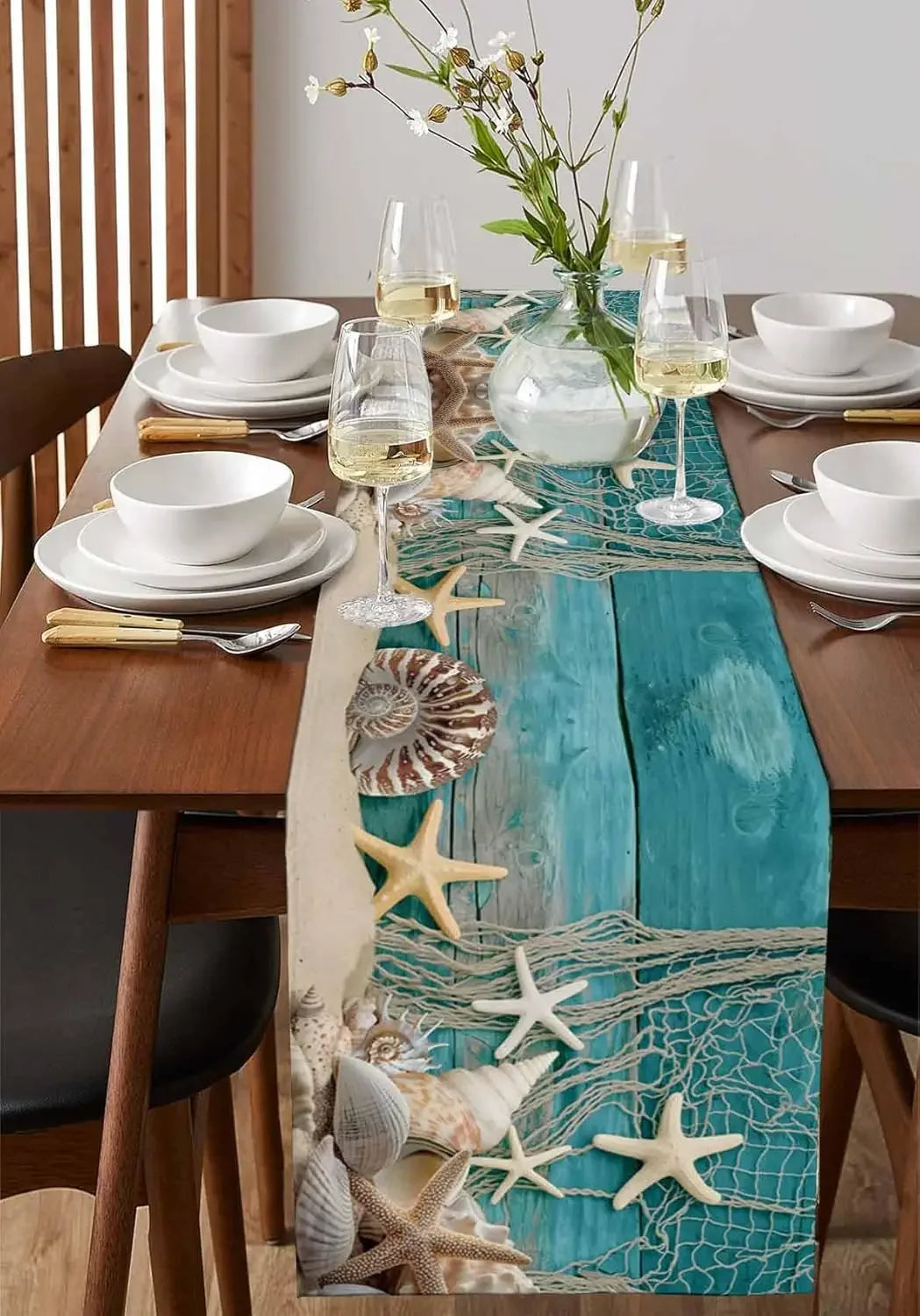 Dining table set with a decorative turquoise runner featuring starfish and shells.