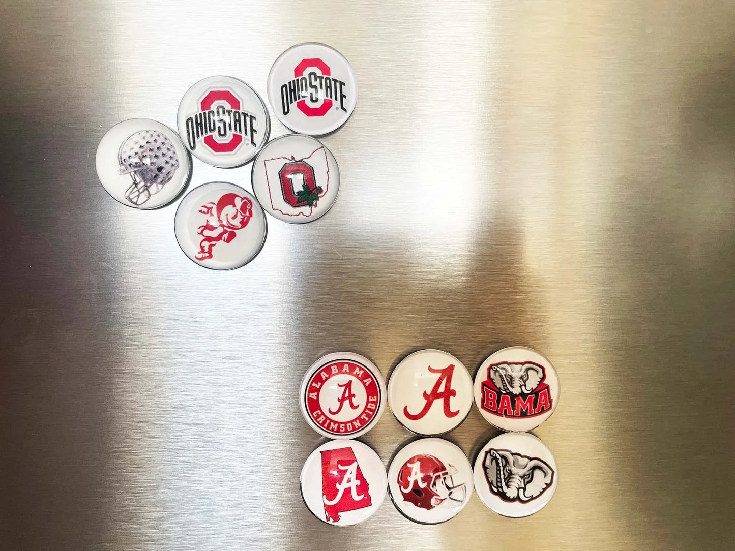 Collection of college team magnets on a metallic surface
