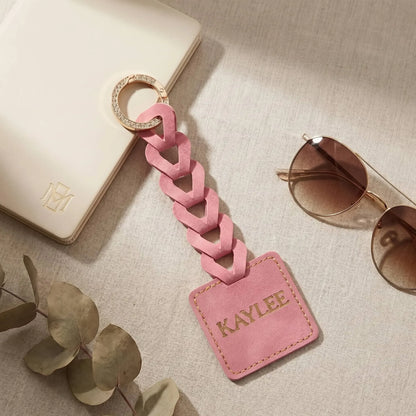 Pink Custom name tag on a neutral surface with sunglasses and leaves.