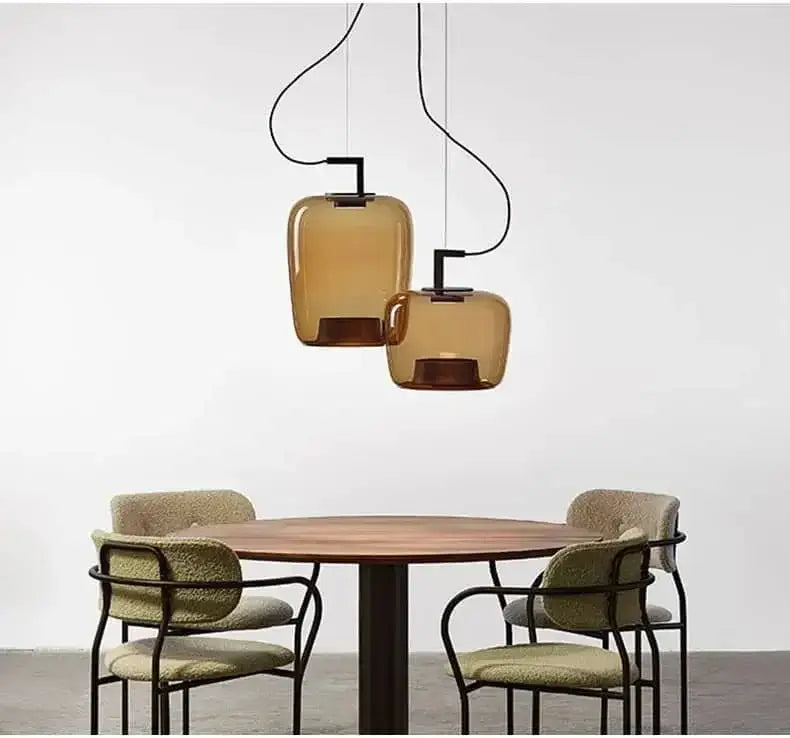 Danish glass pendant light illuminating a dining table with modern chairs in a minimalist setting.