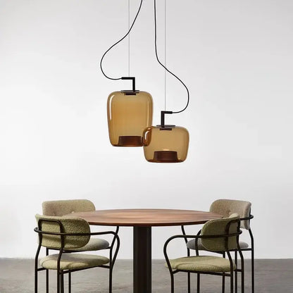 Danish glass pendant light hanging above a round wooden table with stylish chairs.