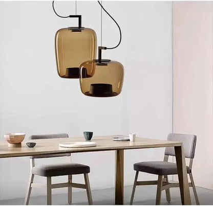 Danish glass pendant light hanging above a modern dining table, featuring sculptural silhouettes and a contemporary design.