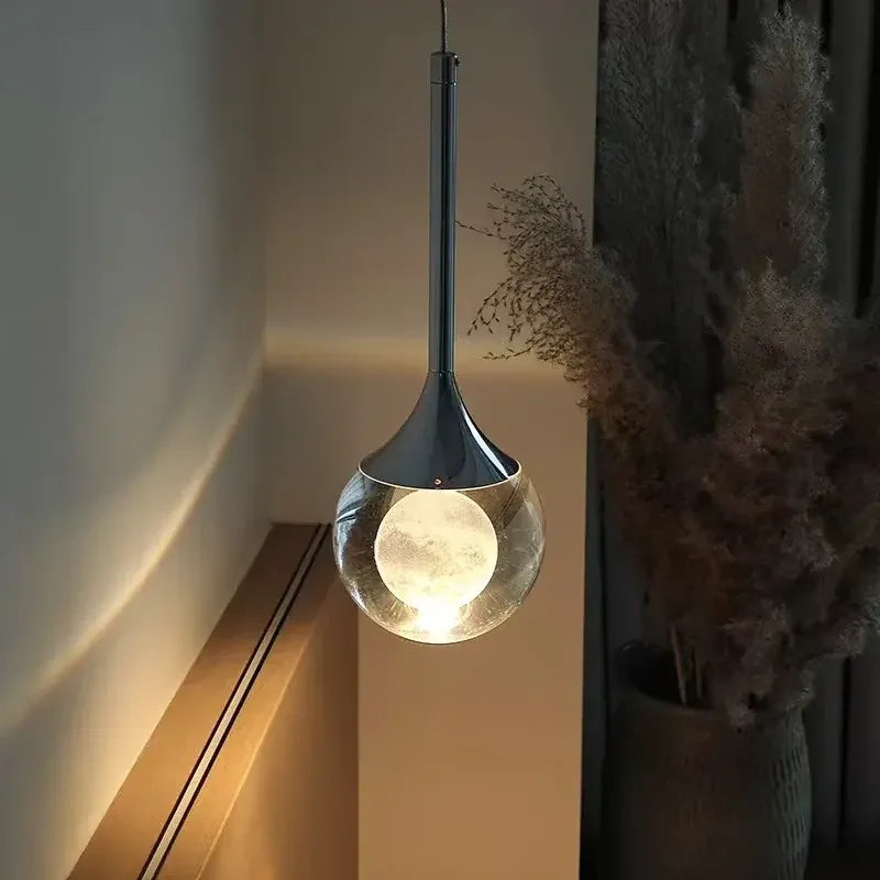 Modern Art Moon Pendant with a glass shade in a softly lit room.