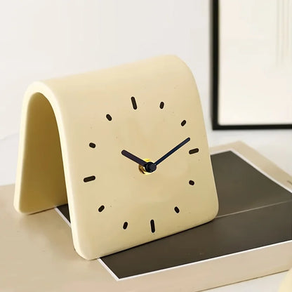 Beige clock on a surface with a white wall in the background