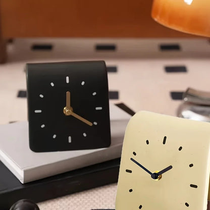 Two clock designs on a surface with a blurred background