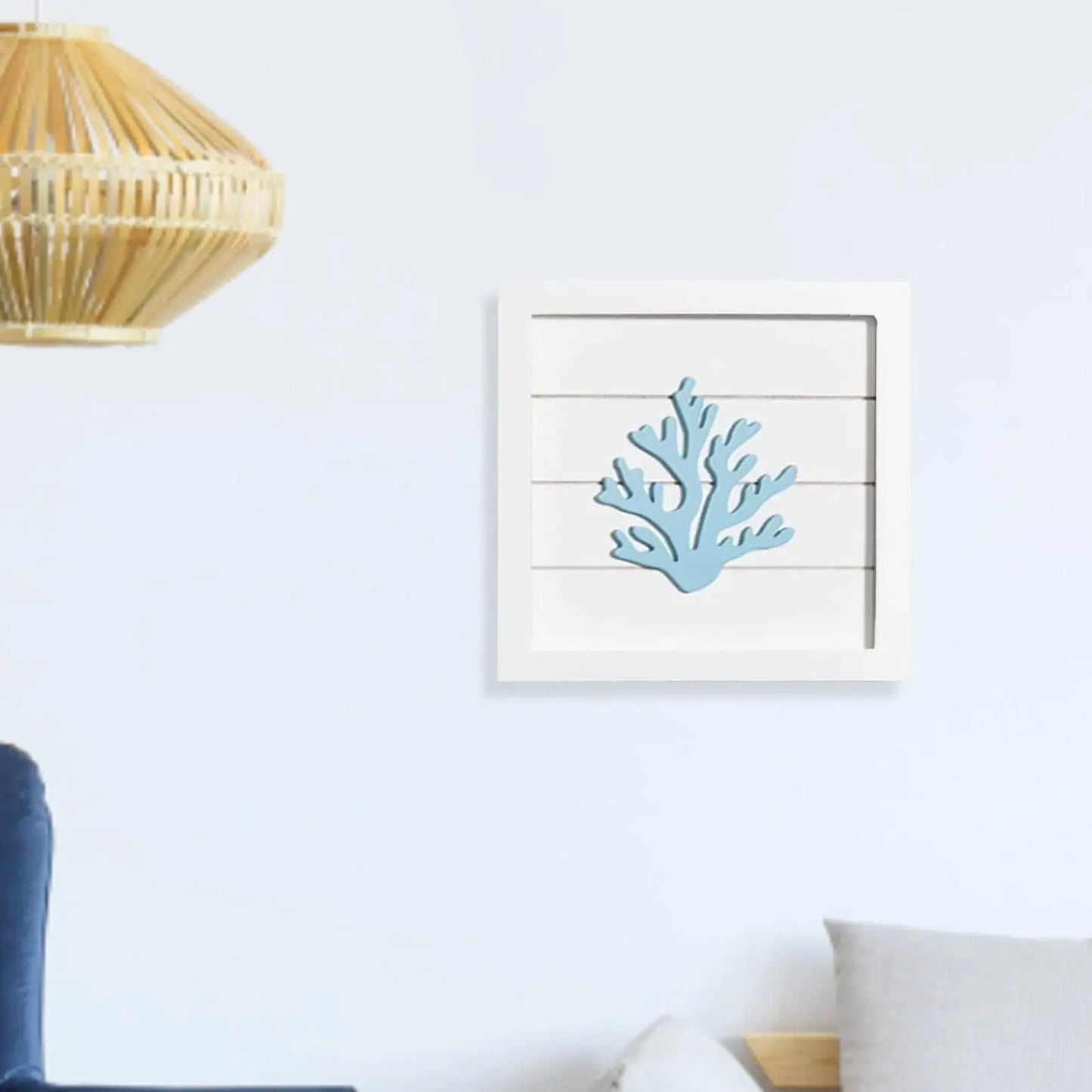 Framed artwork of a blue coral design on a white wall above a sofa.