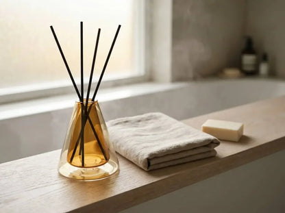 Diffuser with sticks on a bathroom counter with soap and towel