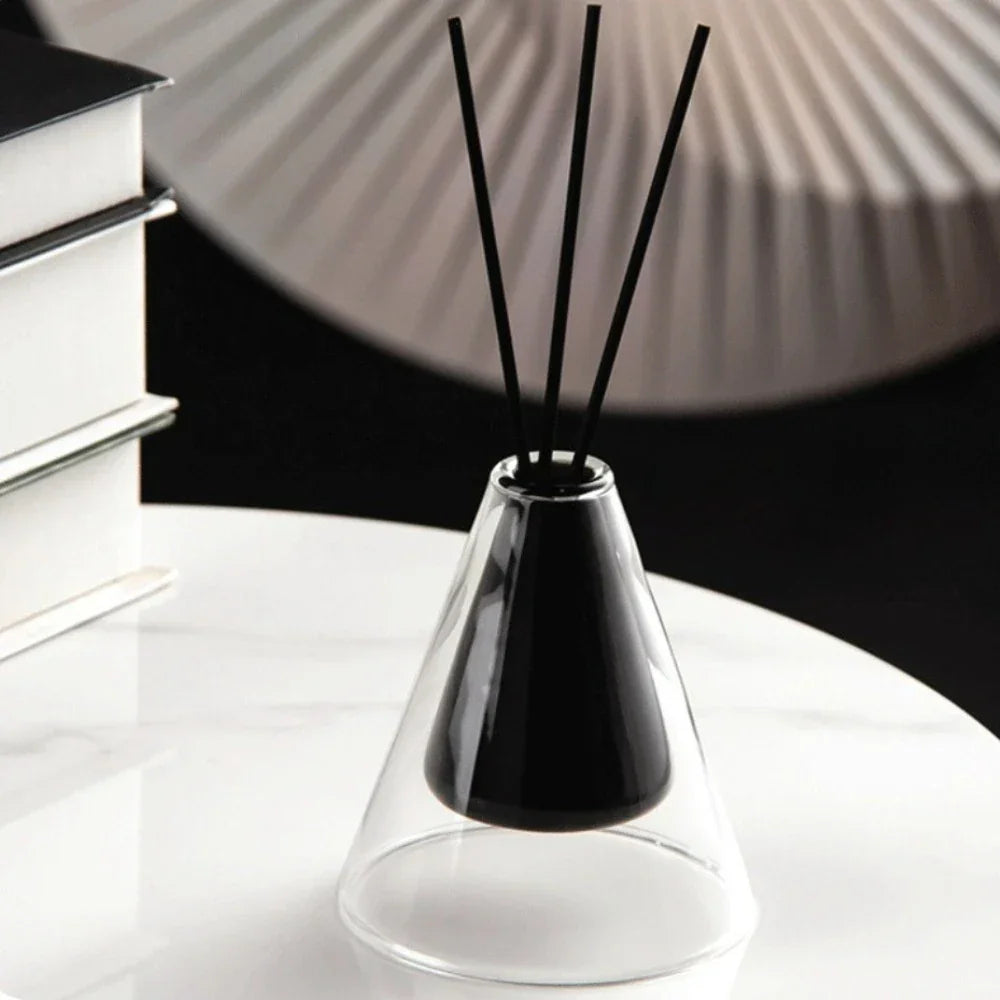 Black diffuser vase with sticks on a white surface