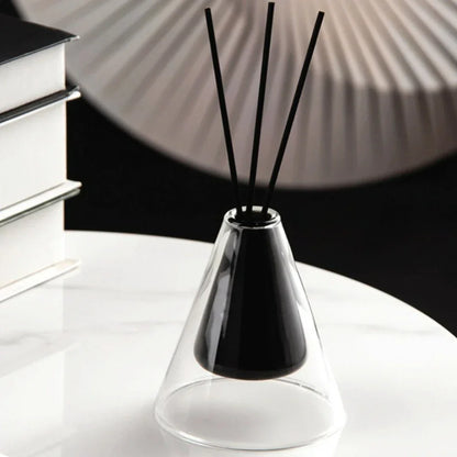Black diffuser vase with sticks on a white surface