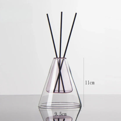 Clear glass diffuser with black sticks inside on a light gray background