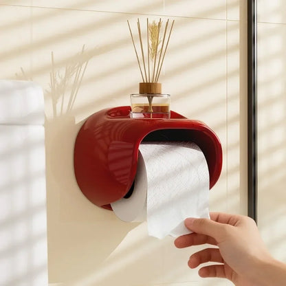 Red wall-mounted paper towel holder with a hand pulling out a roll of paper towels.